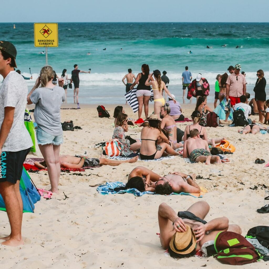 People enjoying a sunny day at Bondi Beach, Australia, with vibrant ocean waves and lively atmosphere.